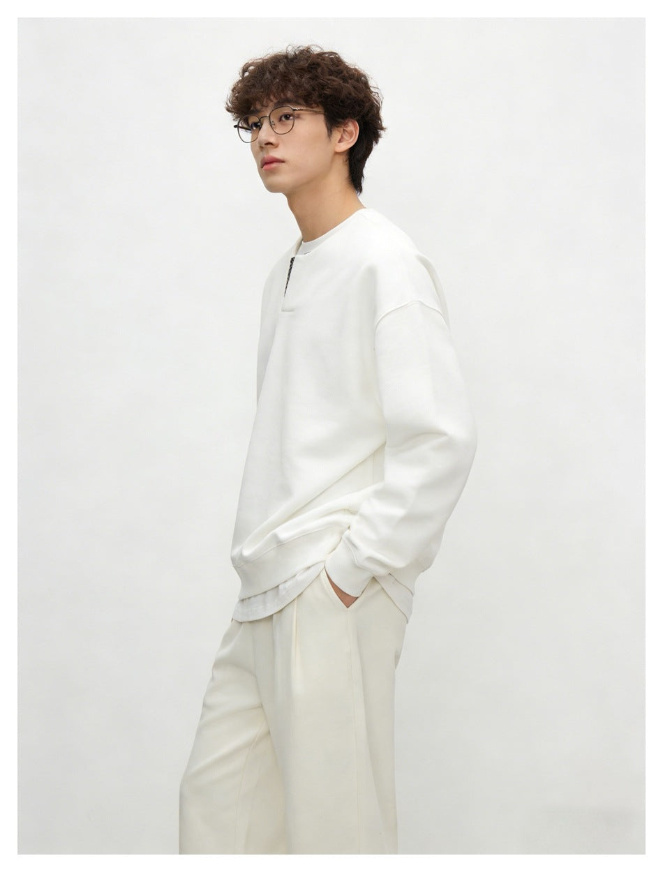 Side view of a model wearing a white sweatshirt with a checked neckline insert and matching trousers.