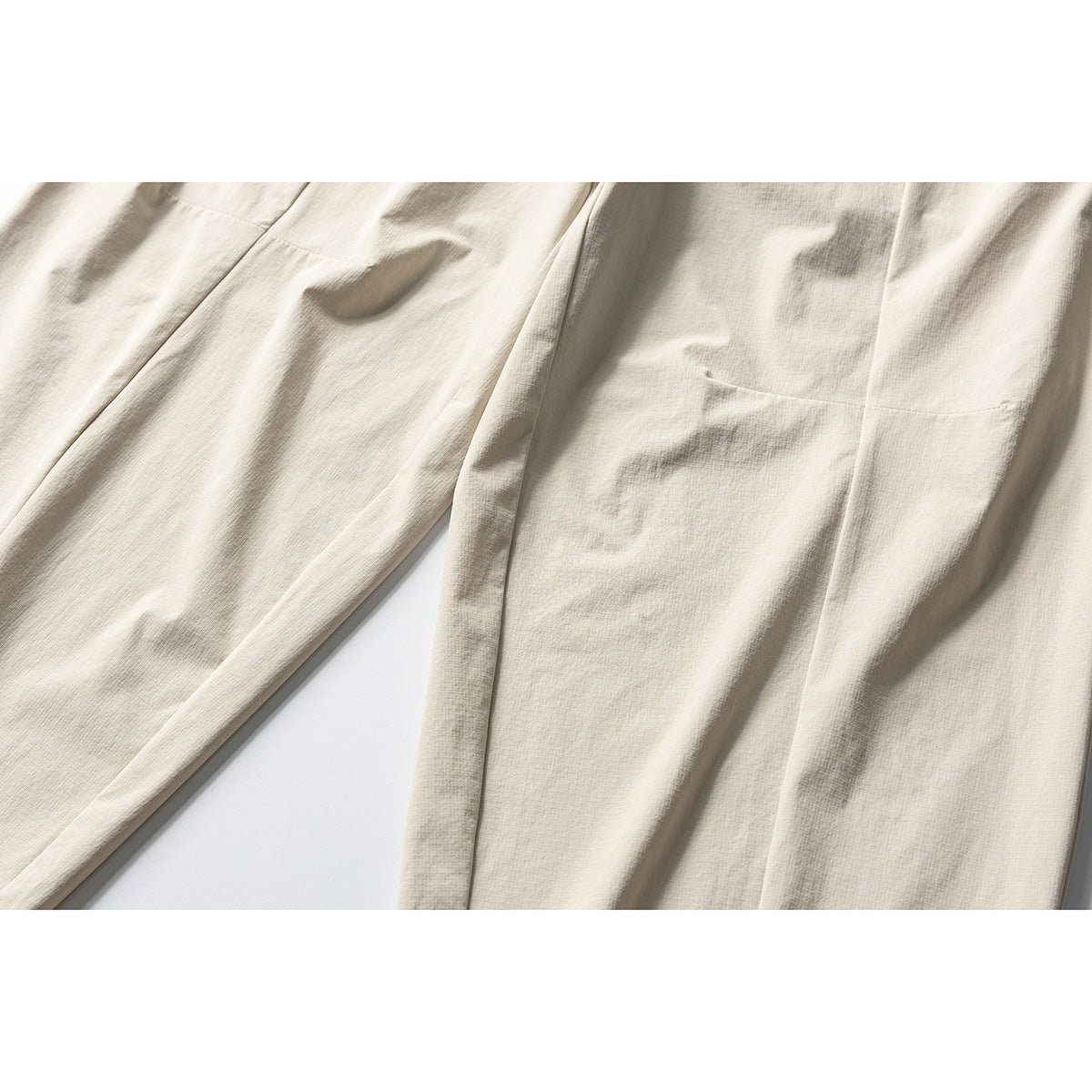 Close-up of cream trousers showing the leg panels, seams and a rectangular patch pocket.