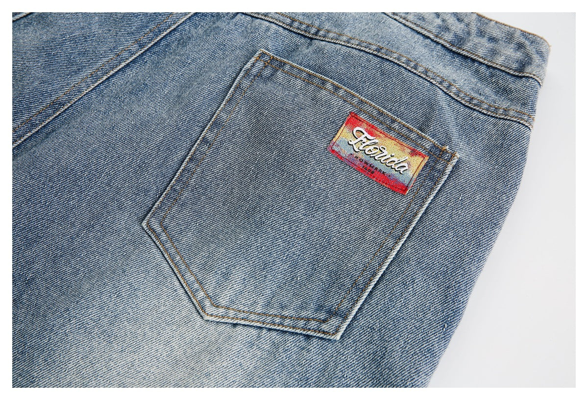 Close-up of a light blue denim back pocket with contrast stitching and a colorful sewn label.