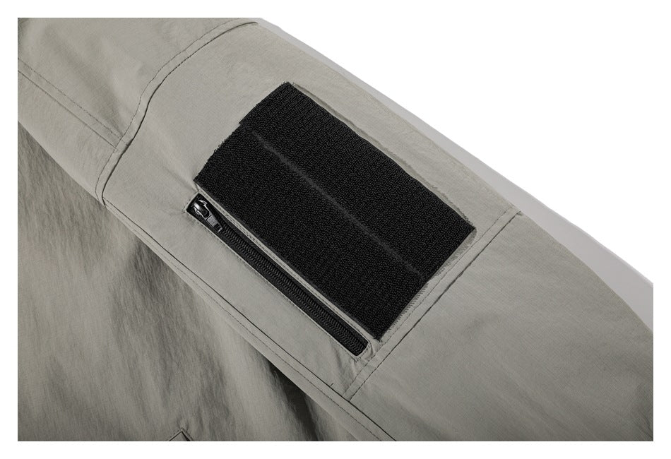 Close-up of a sleeve pocket with a black hook-and-loop panel and zipper.