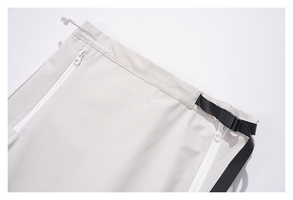 Close-up of the skirt's waistband, white zipper pockets, and black adjustable strap and buckle.