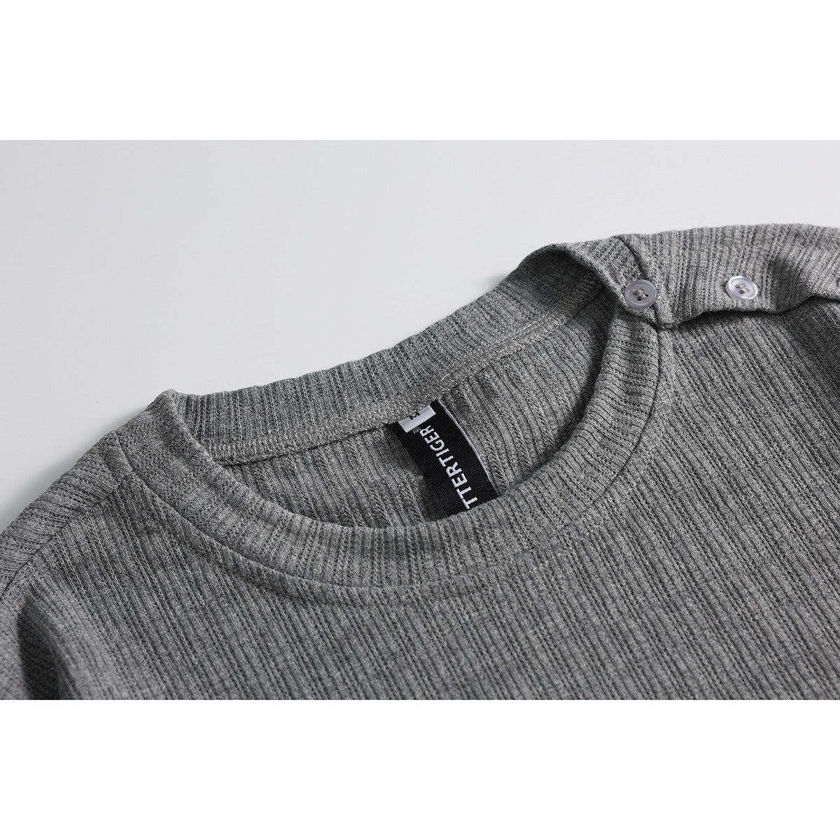 Close-up of a gray ribbed crew-neck T-shirt with two shoulder buttons and a visible neck label.