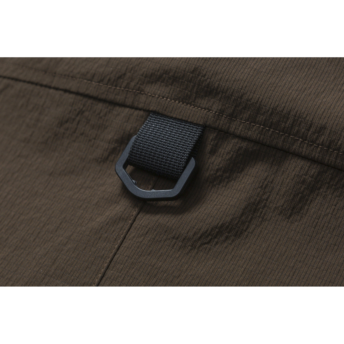 Close-up of a black webbing loop and angular ring attached to dark brown striped fabric.