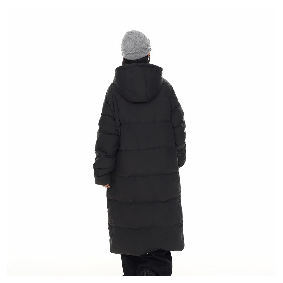 Back view of a model wearing a long black hooded puffer coat and gray knit beanie.