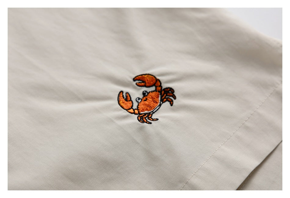 Close-up of an orange crab embroidery on pale beige fabric.