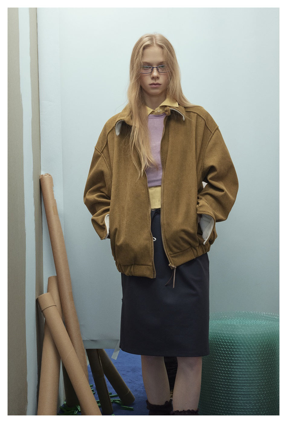 Model wearing an oversized brown ribbed zip jacket with a wide collar and gathered hem.