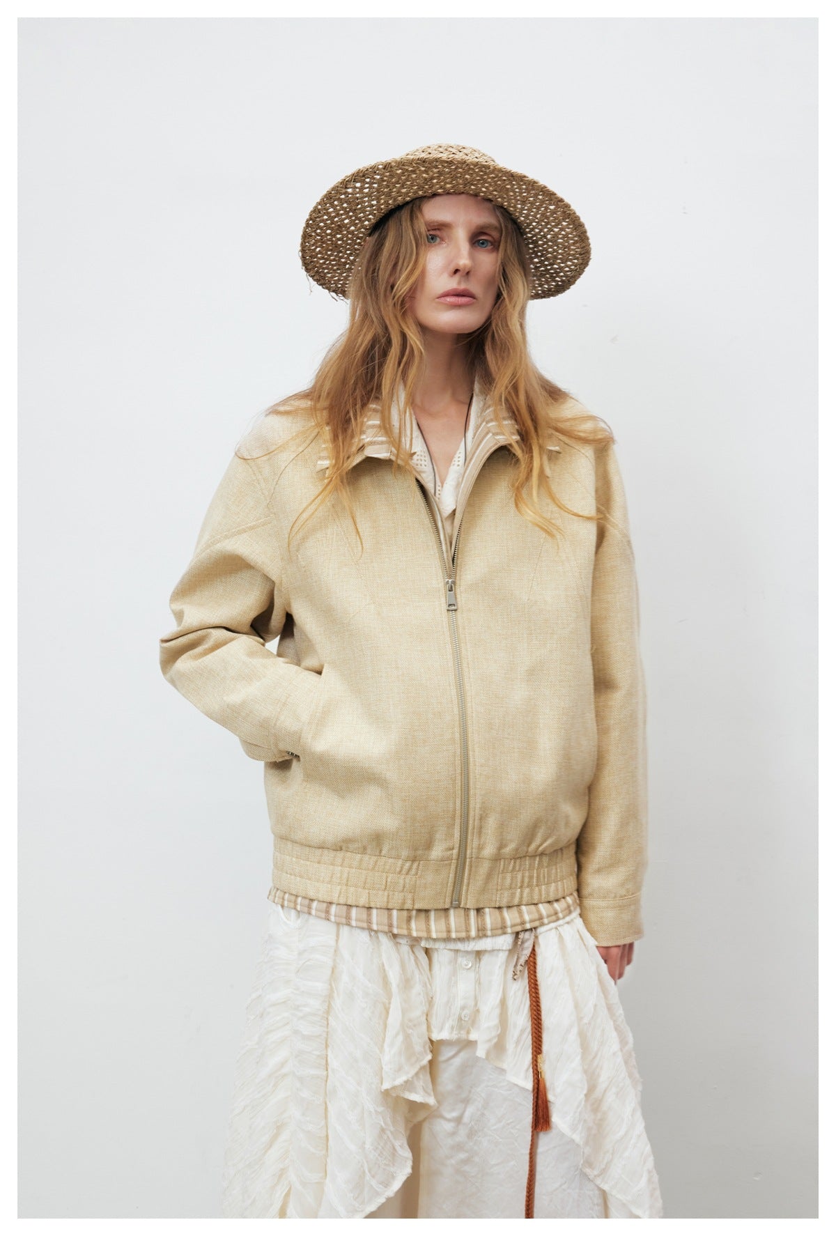 Full view of a model wearing a beige zip-front jacket with striped collar detail and a gathered hem.