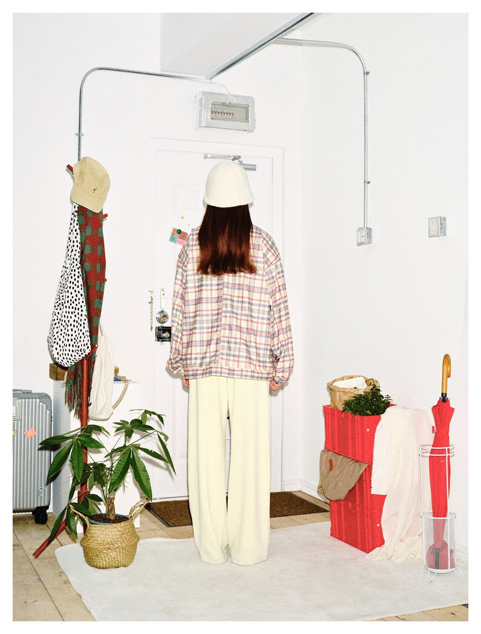 Back view of a model wearing a pastel plaid jacket, cream wide-leg pants, and a white knit hat.