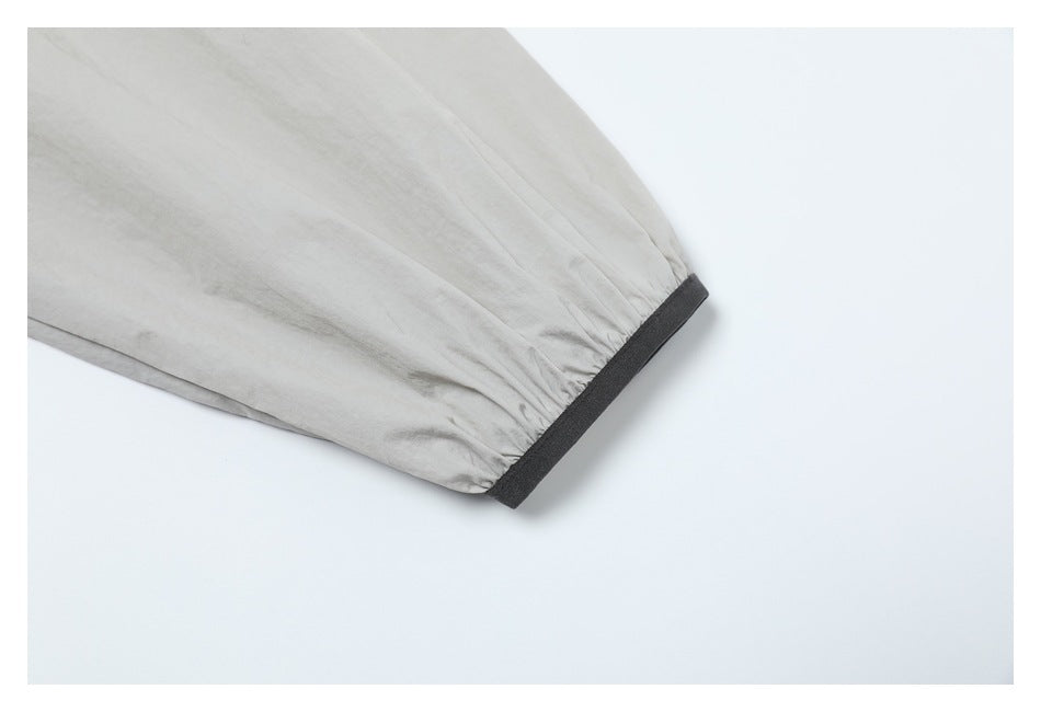Close-up of a light gray jacket sleeve ending in a black cuff band.