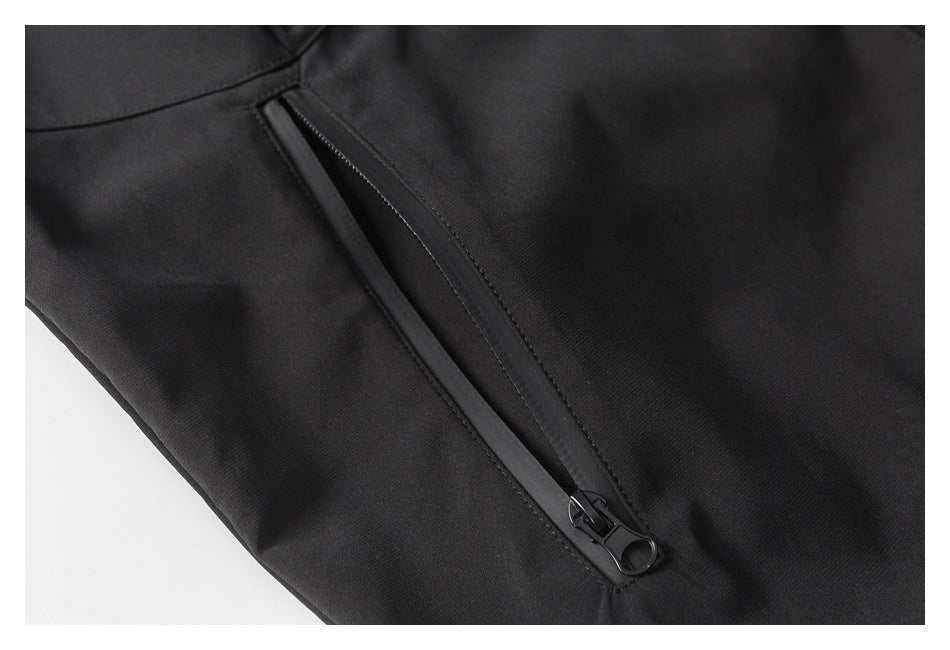 Close-up of a black jacket's angled zipper pocket with a ring-shaped zipper pull.