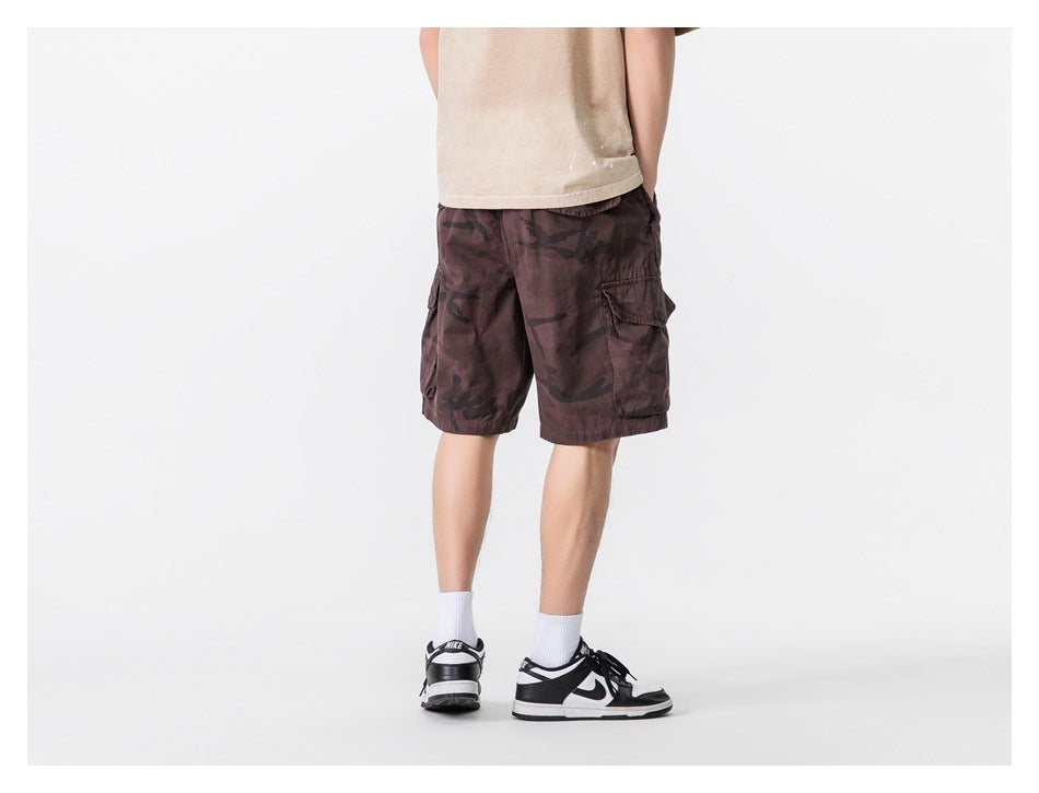 Back view of a model wearing burgundy camouflage cargo shorts with large side cargo pockets.