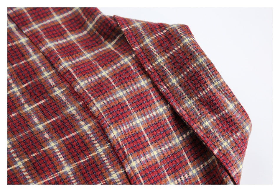 Close-up of red-orange plaid fabric with navy, cream, and tan checks and a folded seam.