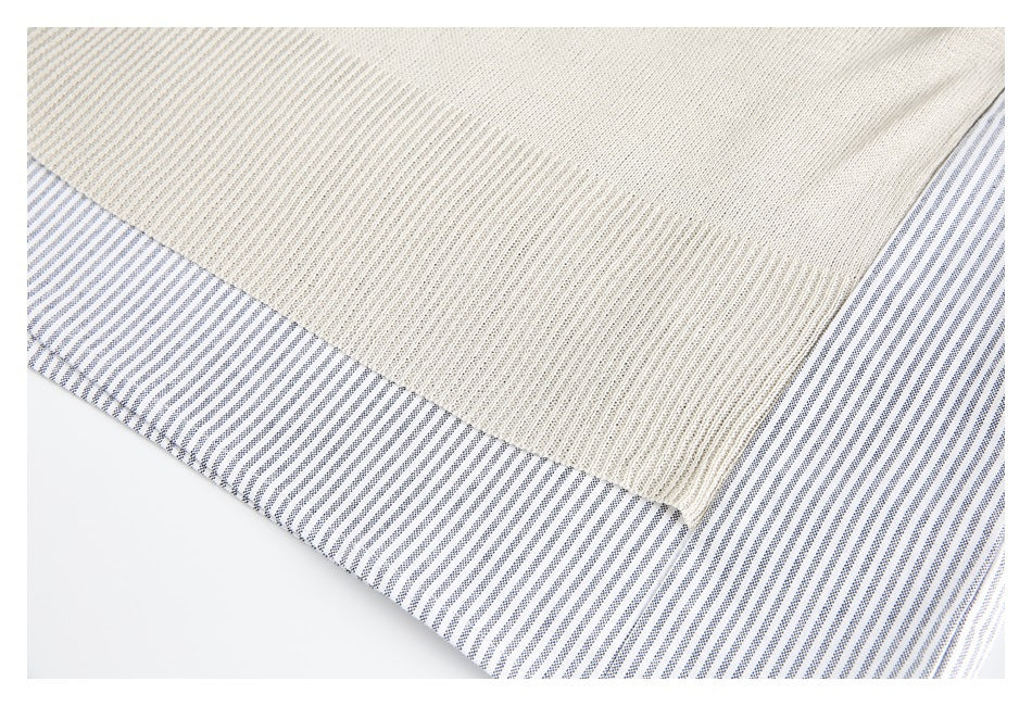 Close-up of a cream textured panel overlapping white fabric with fine navy stripes.