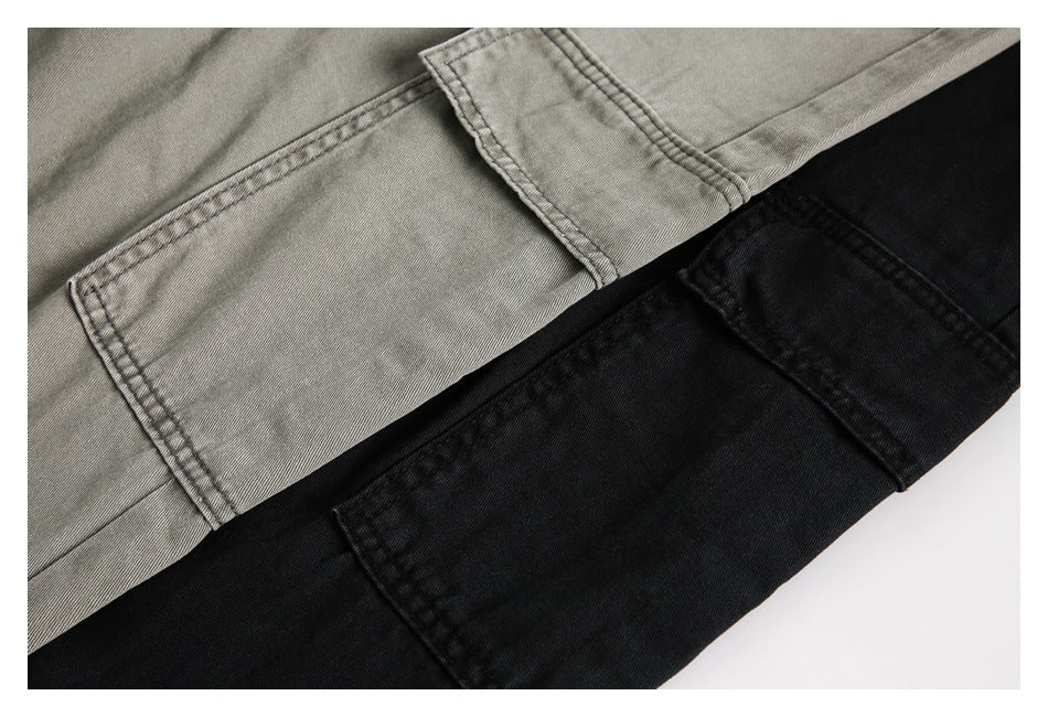 Close-up of gray and black pants showing stitched cargo pocket flaps and fabric panels.