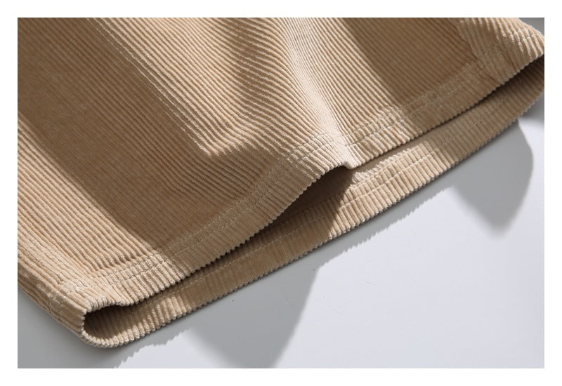 Close-up of the stitched hem on tan corduroy shorts.