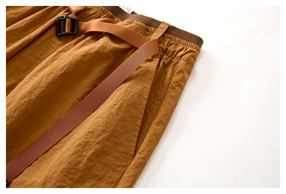 Angled close-up of rust-brown shorts showing the belt, gathered waistband, and side seam.