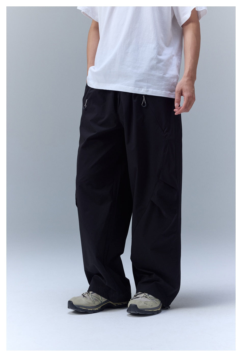 Front view of a person wearing loose black pants with zip pockets and a white T-shirt.