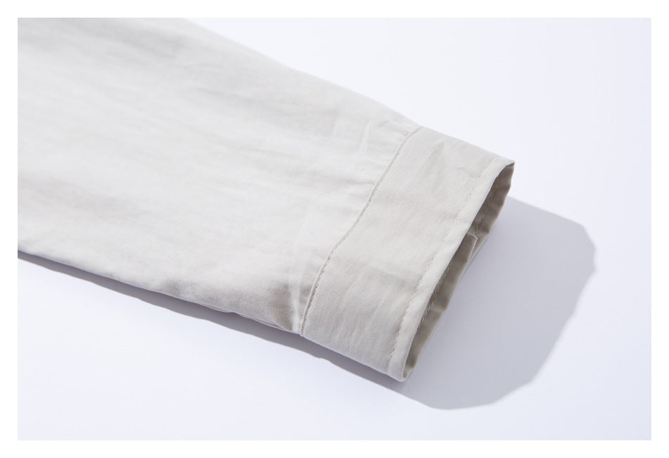 Close-up of a white shirt sleeve and wide stitched cuff laid flat.