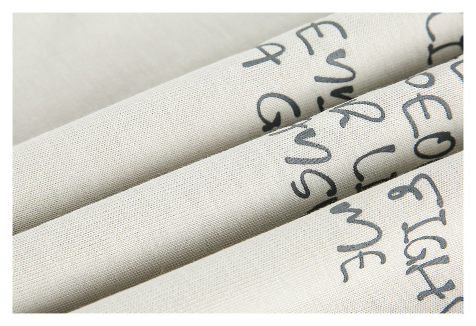 Macro view of ivory shirt fabric folded to show parts of its dark handwritten-style print.