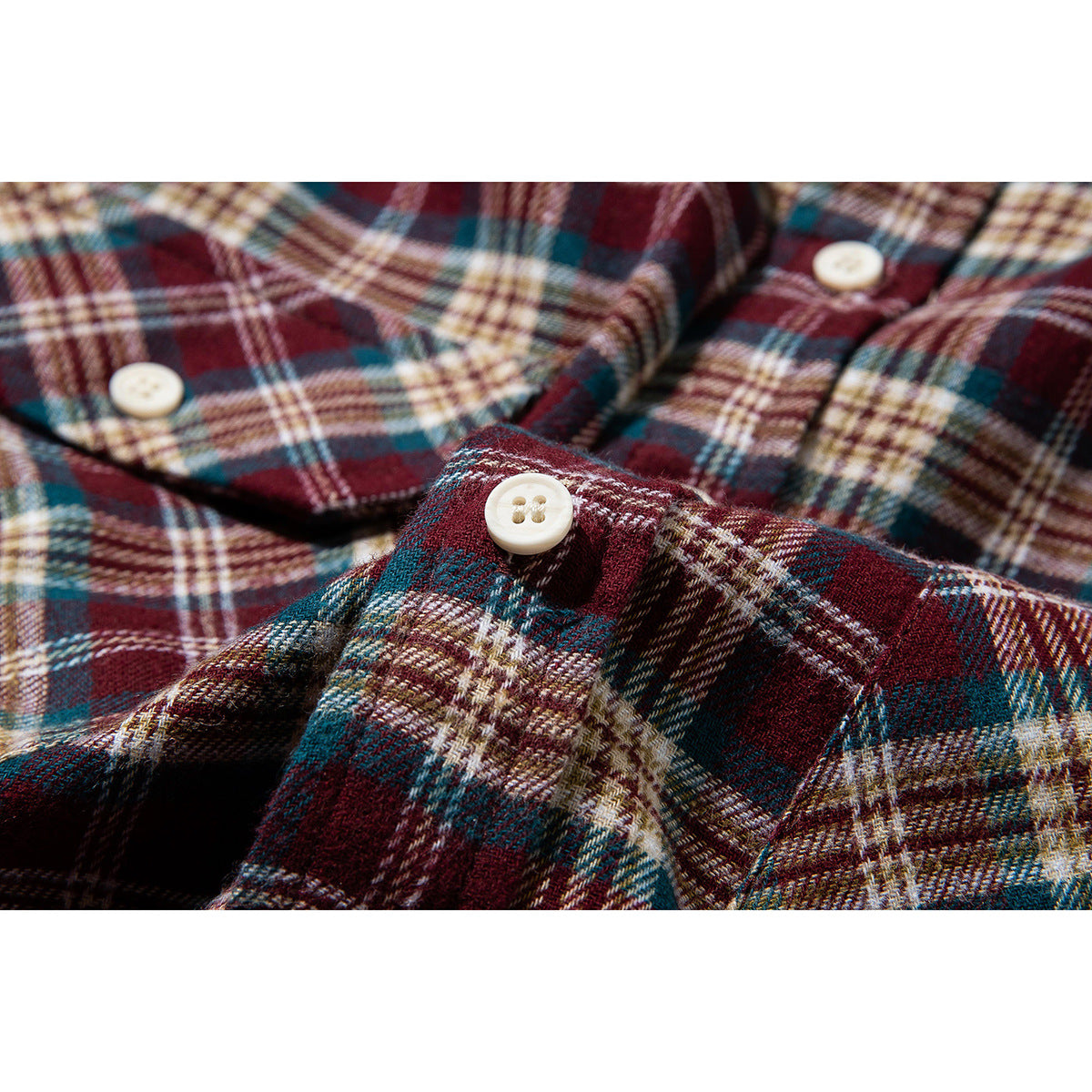 Close-up of cream buttons and burgundy, teal, and cream plaid shirt fabric.