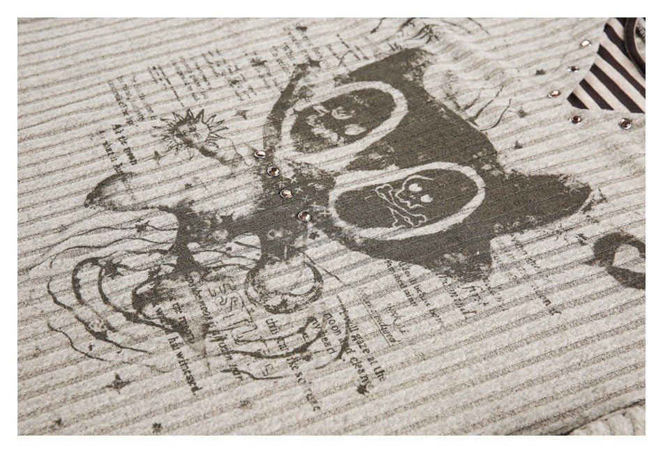 Close-up of a distressed skull graphic and newspaper-style print on a gray striped top.