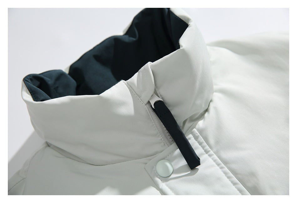 Close-up of the white jacket's high collar, black zipper pull, and snap-fastened front placket.