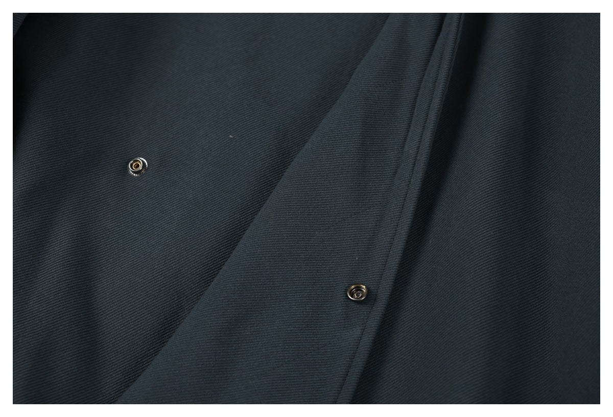 Close-up of the dark charcoal jacket's overlapping front placket with two metal snap fasteners.