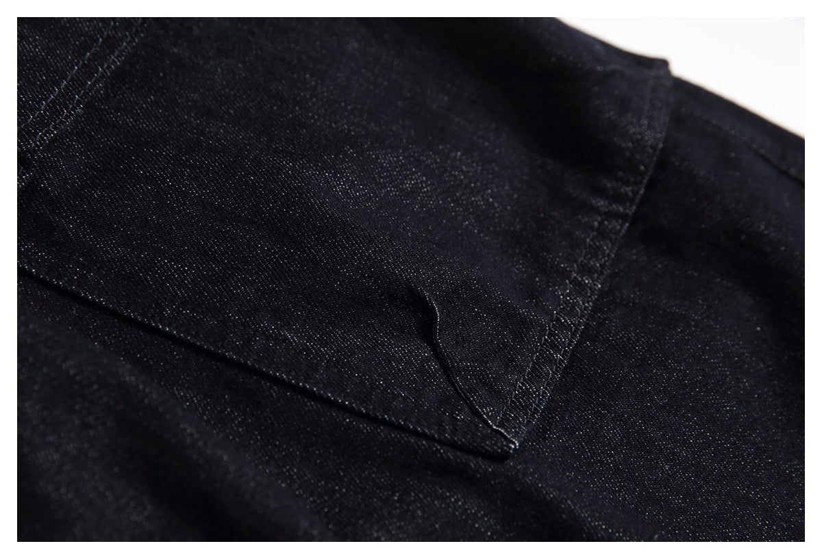 Close-up of a stitched pocket on black jeans with visible denim texture.
