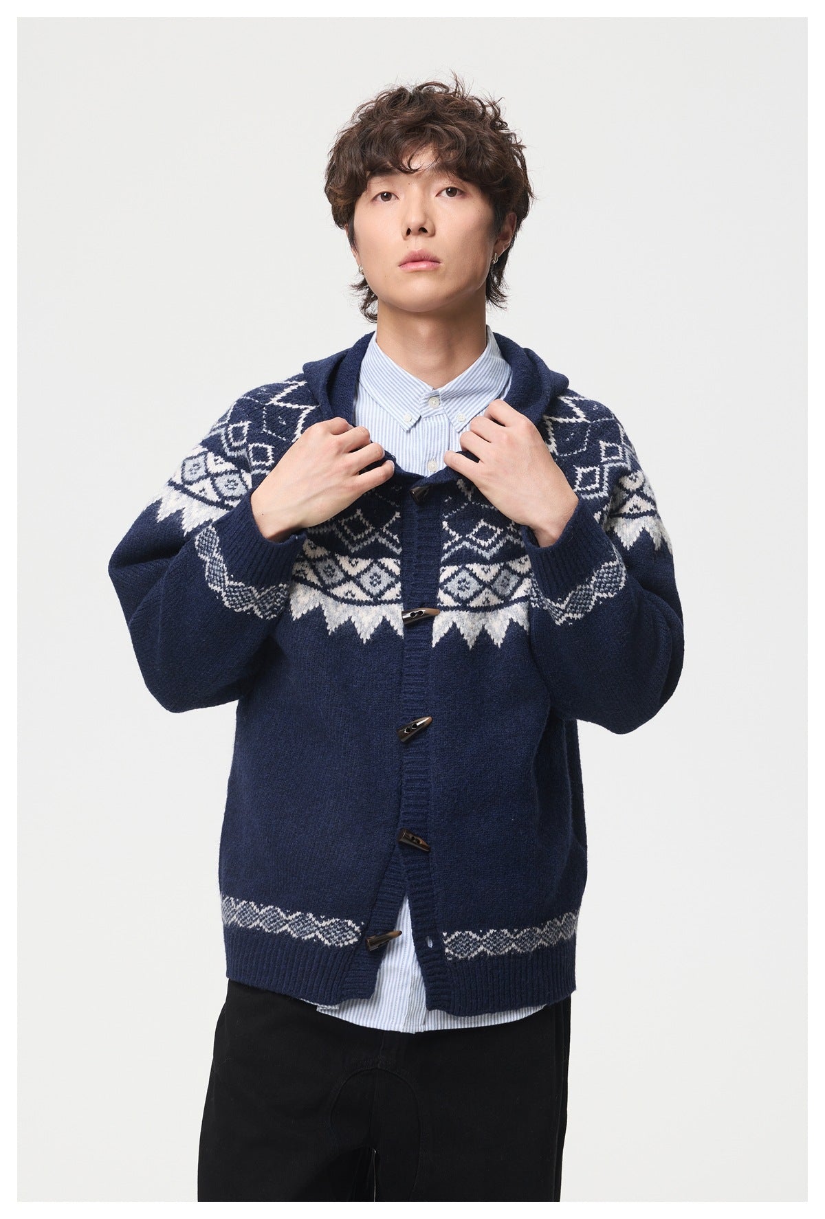 Close front view of a model in a navy hooded cardigan with cream geometric bands and toggle closures.