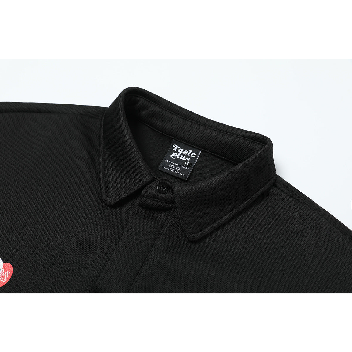 Close-up of a black polo collar, button, and neck label; part of a small red-and-white chest emblem appears at the edge.