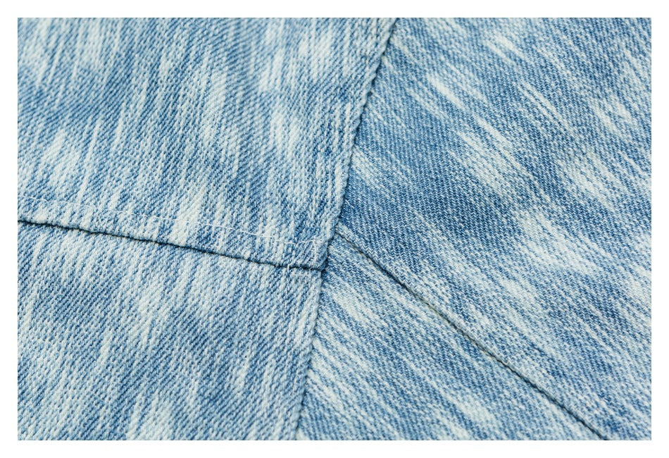 Close-up of light blue washed denim panels with stitched seams.
