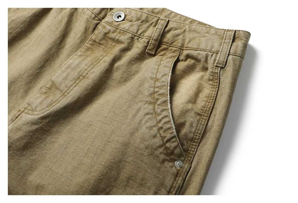 Close-up of tan cargo pants showing the waistband, belt loops, button, and curved front pocket.