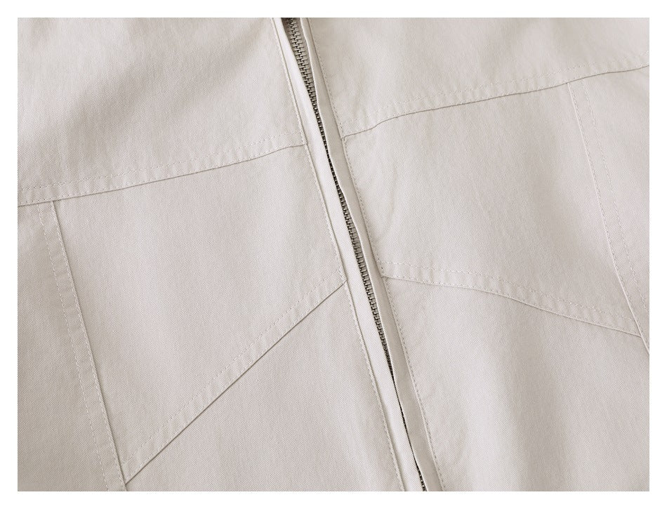 Close-up of the beige jacket's front zipper and large stitched lower pockets.