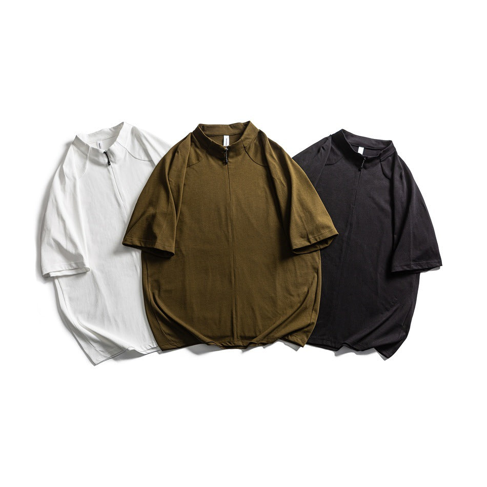 Three short-sleeve zip-neck tops laid flat in white, olive, and black.