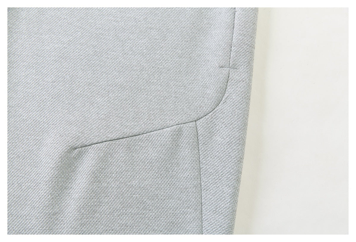 Close-up of pale gray textured garment showing curved panel seams and stitching.
