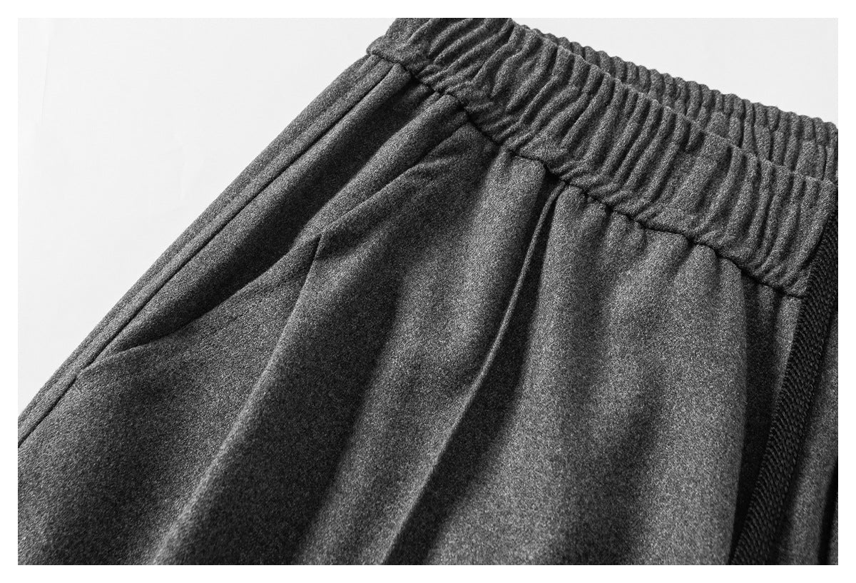 Close-up of charcoal-gray pants showing the gathered elastic waistband, pleats, and side seam.