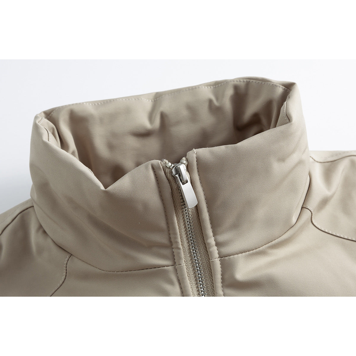 Close-up of a beige jacket's tall stand collar and central front zipper.