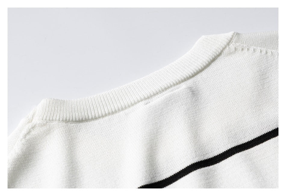 Close-up of the white sweater's ribbed crew neckline and a thin black stripe across the chest.