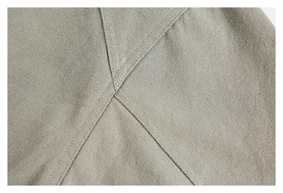 Close-up of gray-khaki fabric panels meeting at intersecting stitched seams.