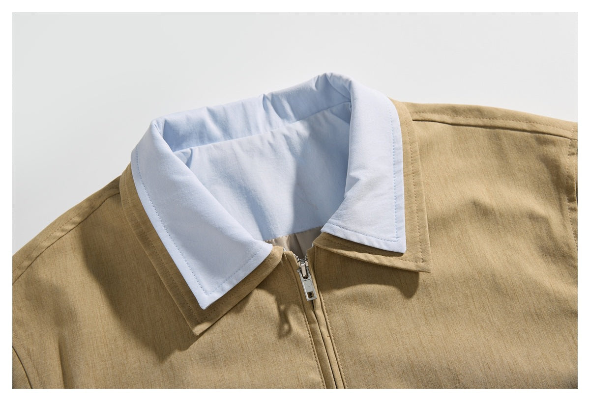 Close-up of a tan jacket's front zipper and contrasting white pointed collar.