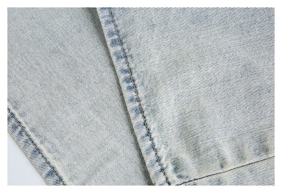 Close-up of stitched panel seams and faded wash on pale blue denim.