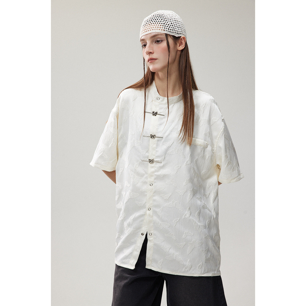 Front view of a model in a white butterfly-patterned short-sleeve shirt with frog closures.