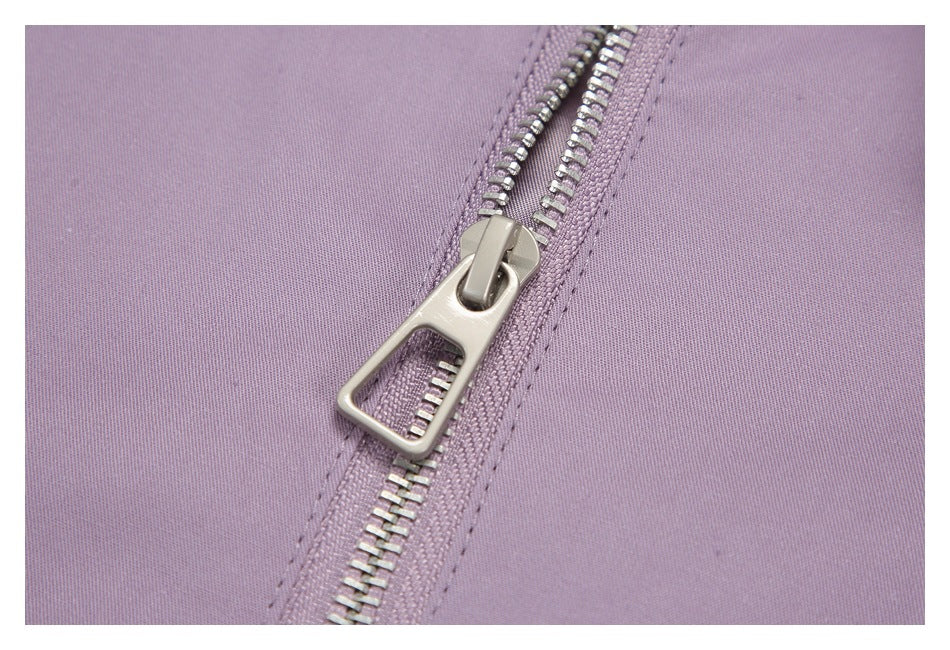 Close-up of the silver zipper and stitching on mauve fabric.