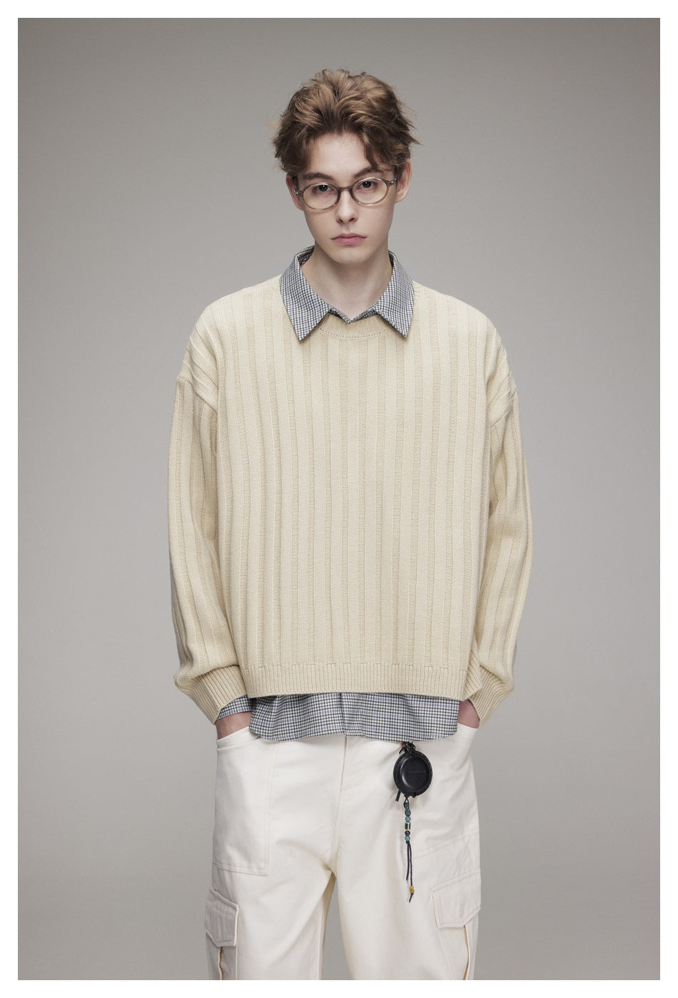 Model facing front in a cream wide-rib crew-neck sweater layered over a checked shirt with off-white cargo pants