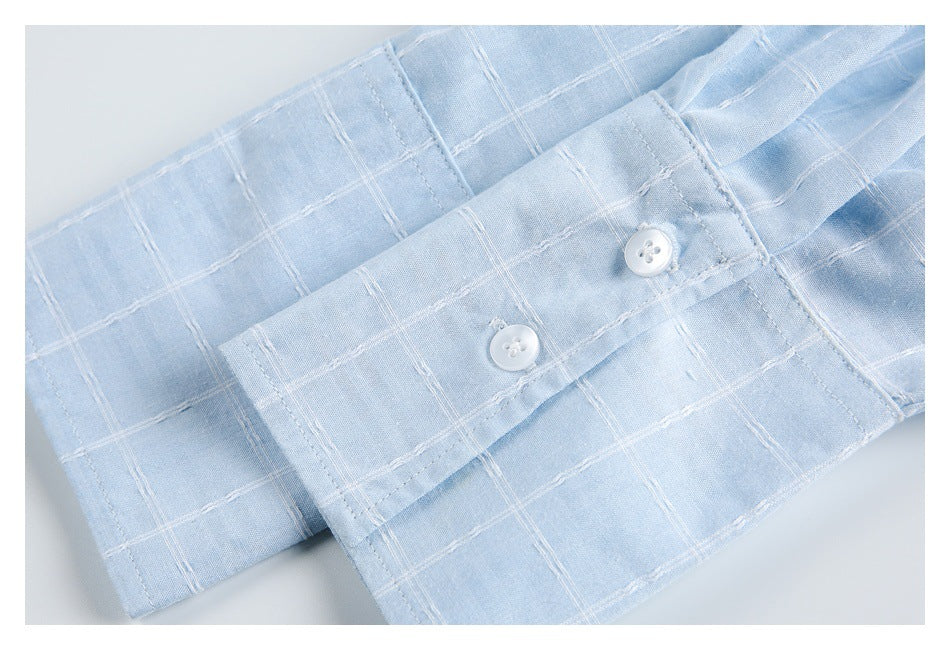 Close-up of a pale blue shirt cuff with two white buttons and white windowpane stitching.