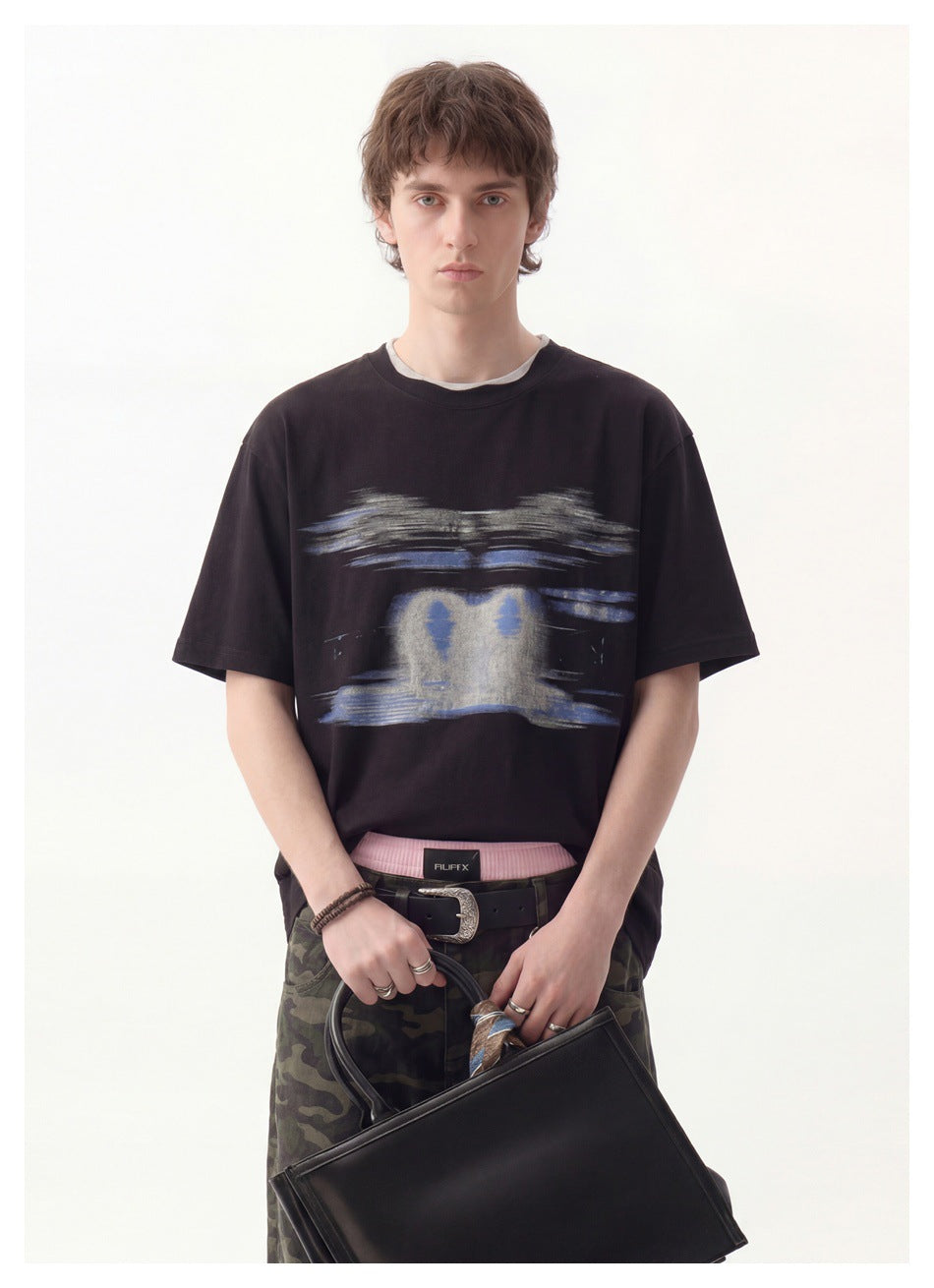 Front view of a model wearing a black T-shirt with a large abstract blue-gray graphic across the chest.