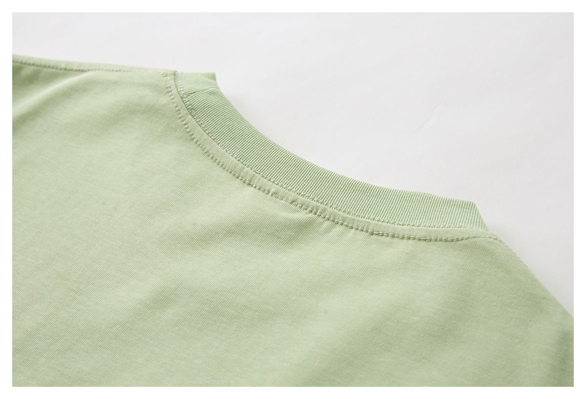 Close-up of a ribbed crew neckline and shoulder seam on a pale green garment.