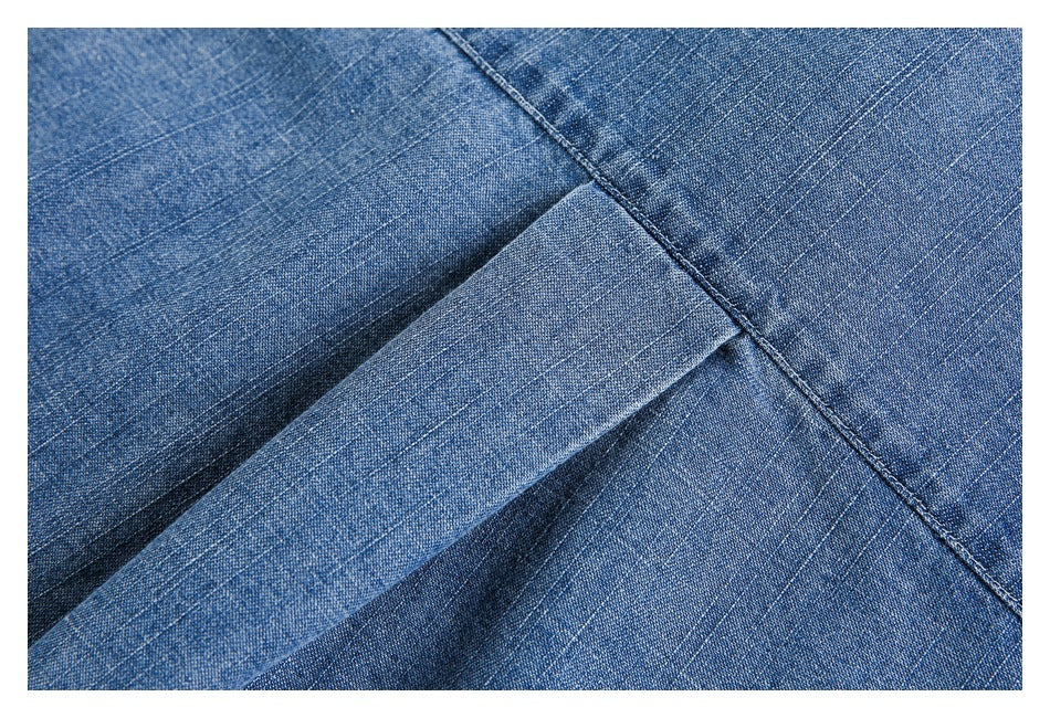 Close-up of blue denim fabric showing a folded edge and intersecting stitched seams.