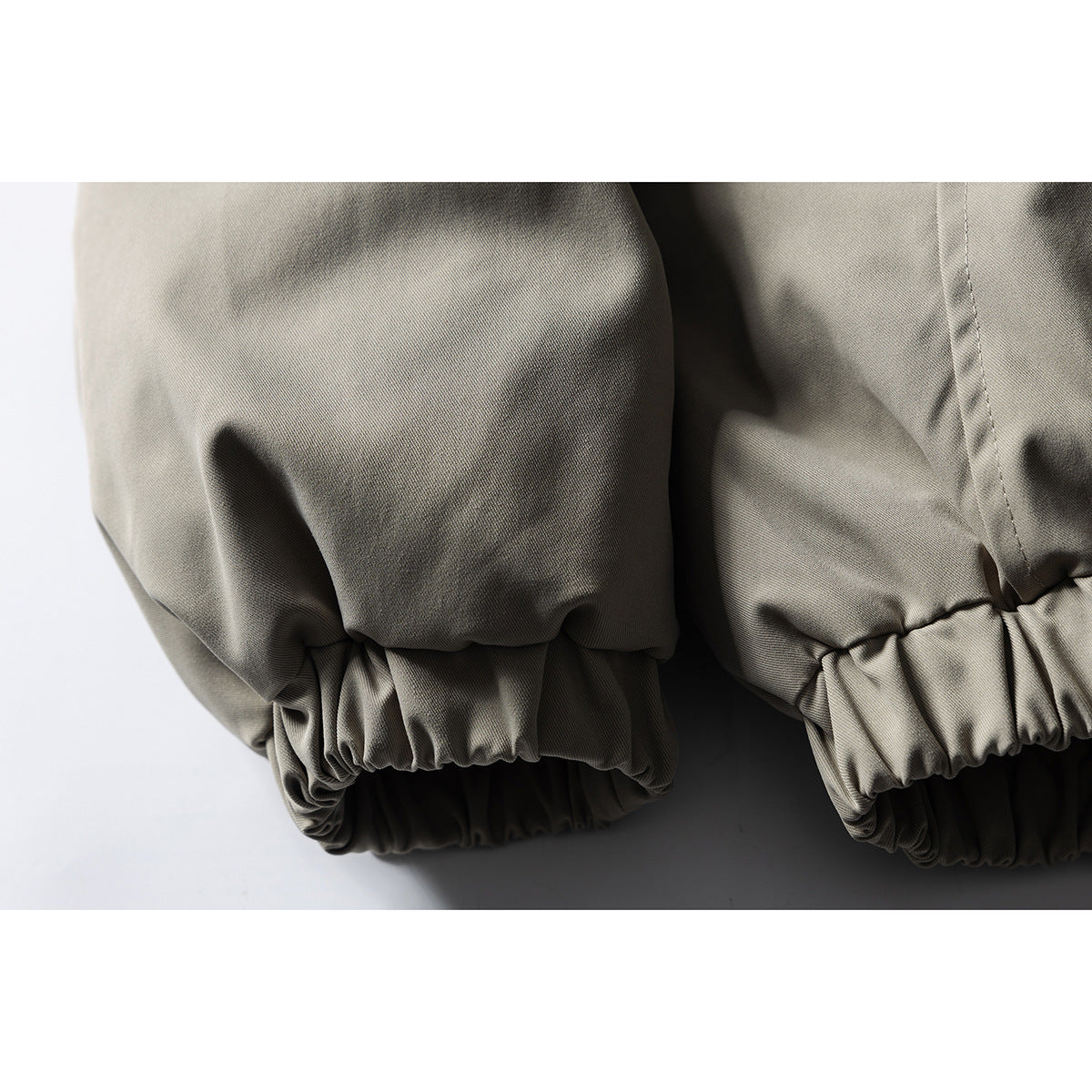 Close-up of the gray-beige jacket's gathered elastic cuffs and hem.