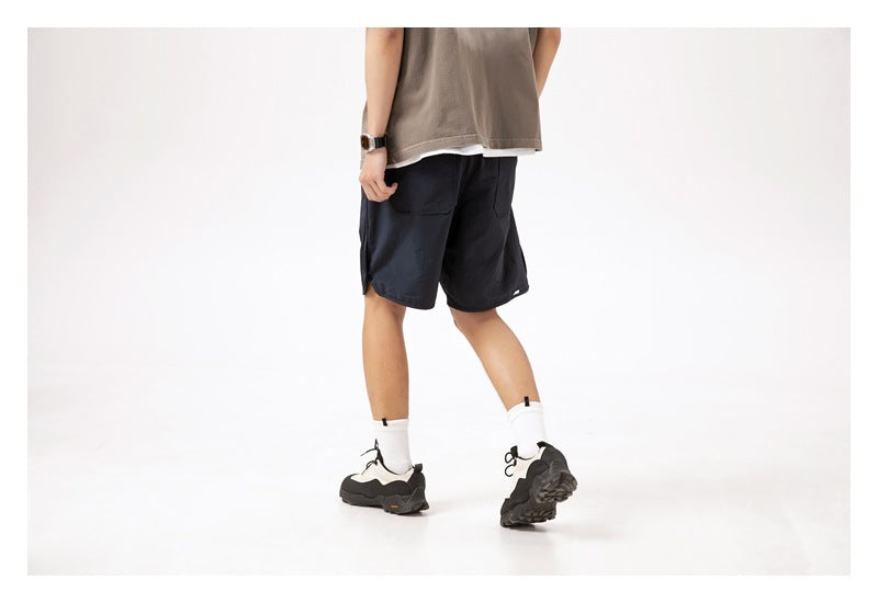 Back view of a person wearing dark navy knee-length shorts and a taupe top.